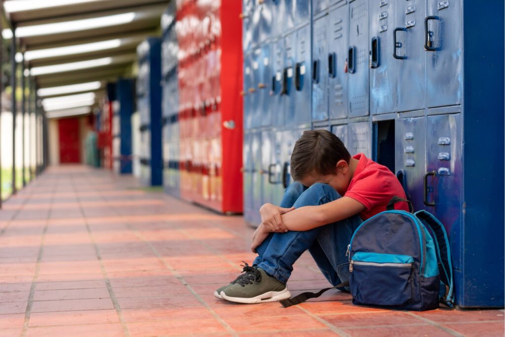 dijete na školskom hodniku s glavom na koljenima