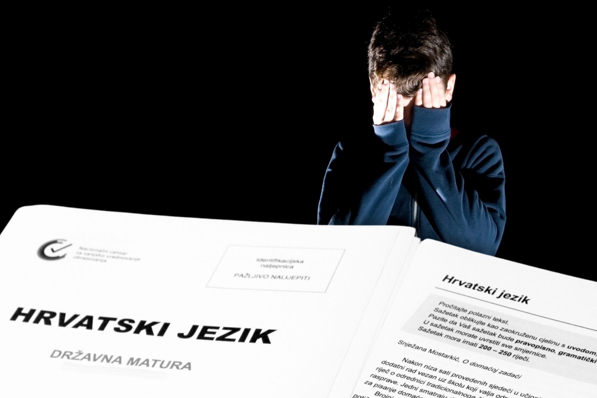 dječak d rukama na glavi kao da plače, ispred papiri državne mature na kojoj piše hrvatski