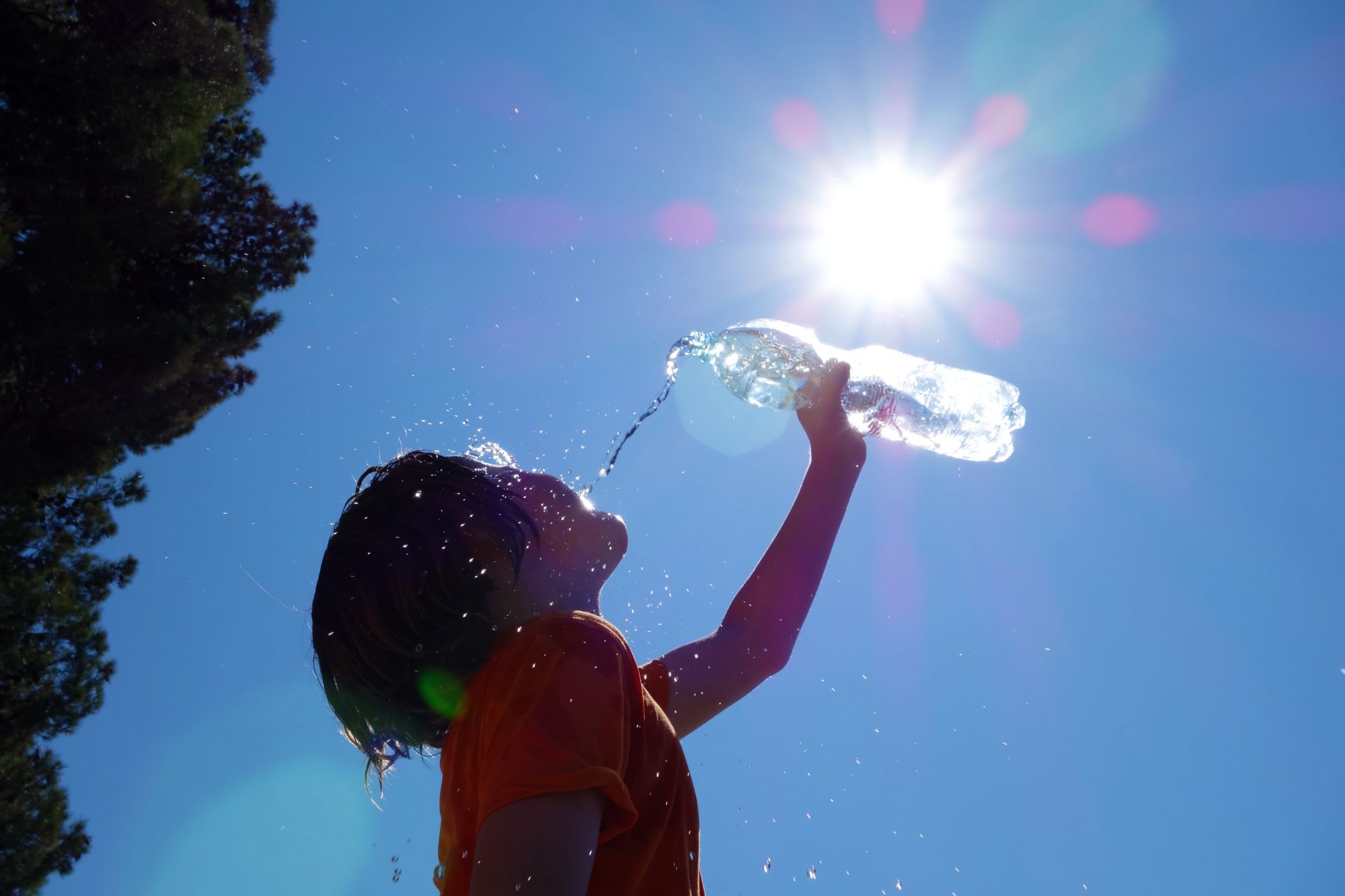 dijete se na suncu polijeva bocom vode